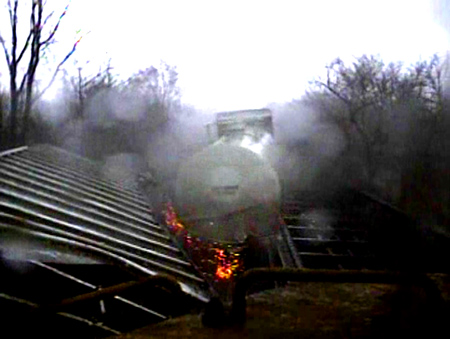 This is a still from video footage you are about to see, the tank car you are seeing is STILL moving being pushed by other freight cars on the track, the tank car seconds from hitting the back of the engine.  